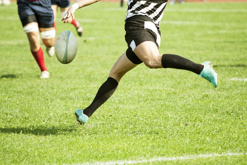 rugby player kicking the ball in open play